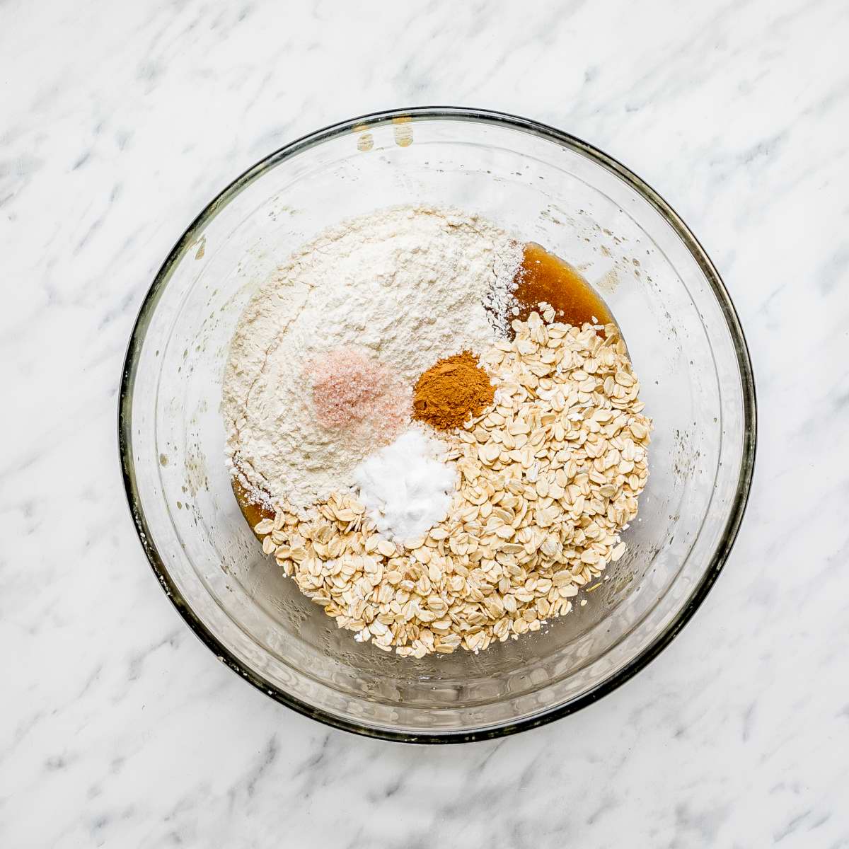Glass bowl with oats, flour, cinnamon, salt, and soda.