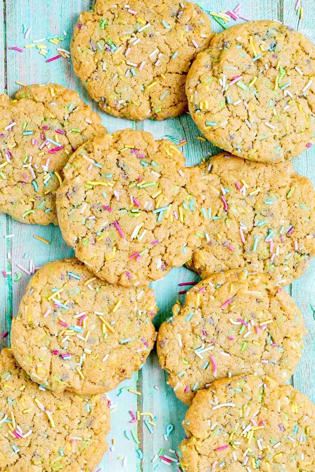 Light brown cookies with rainbow sprinkles on a blue wooden surface.