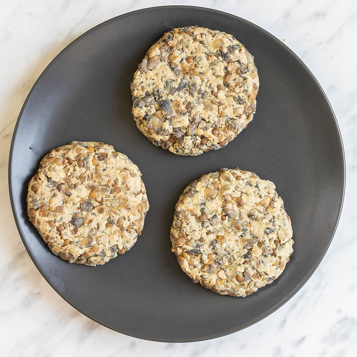 3 lentil patties on a black plate.