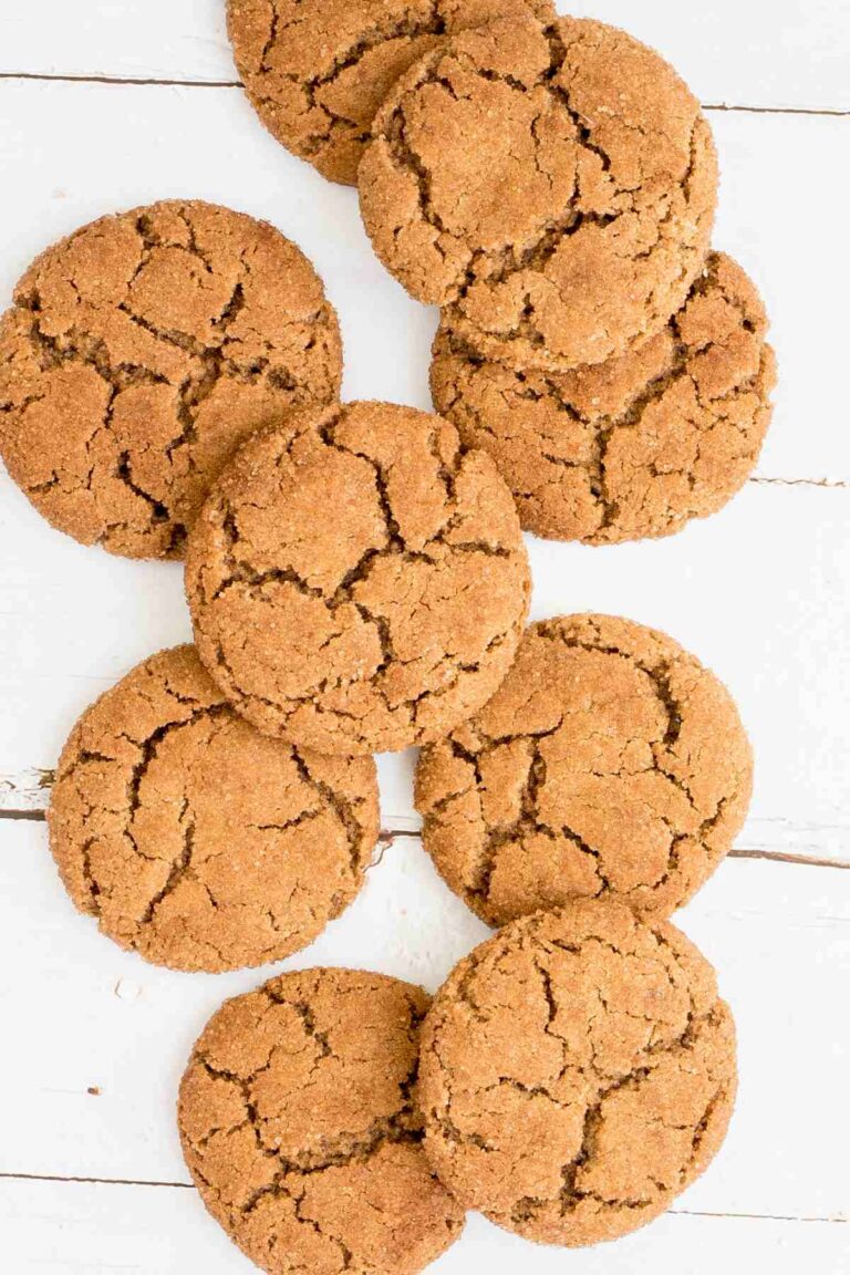 Light brown cookies with crinkled top on a white wooden surface.