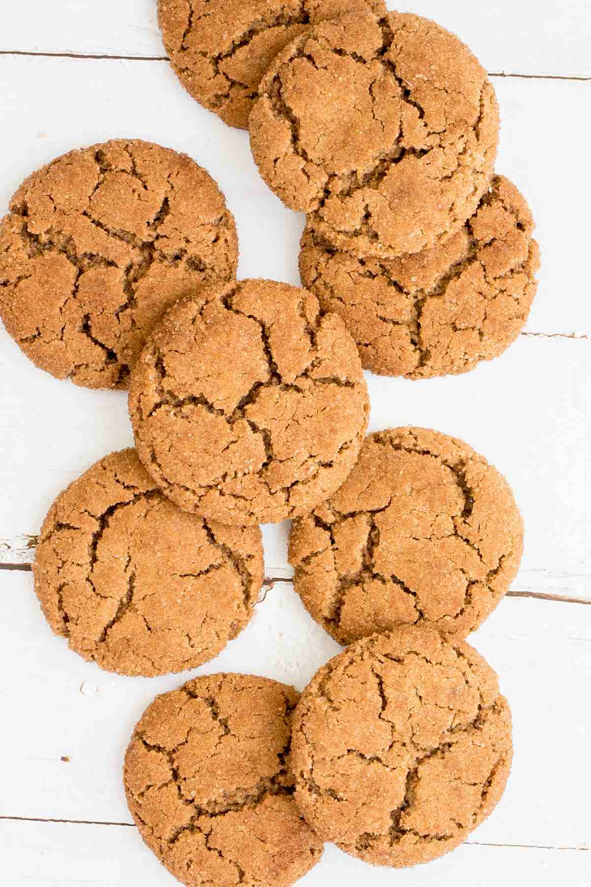 Light brown cookies with crinkled top on a white wooden surface.