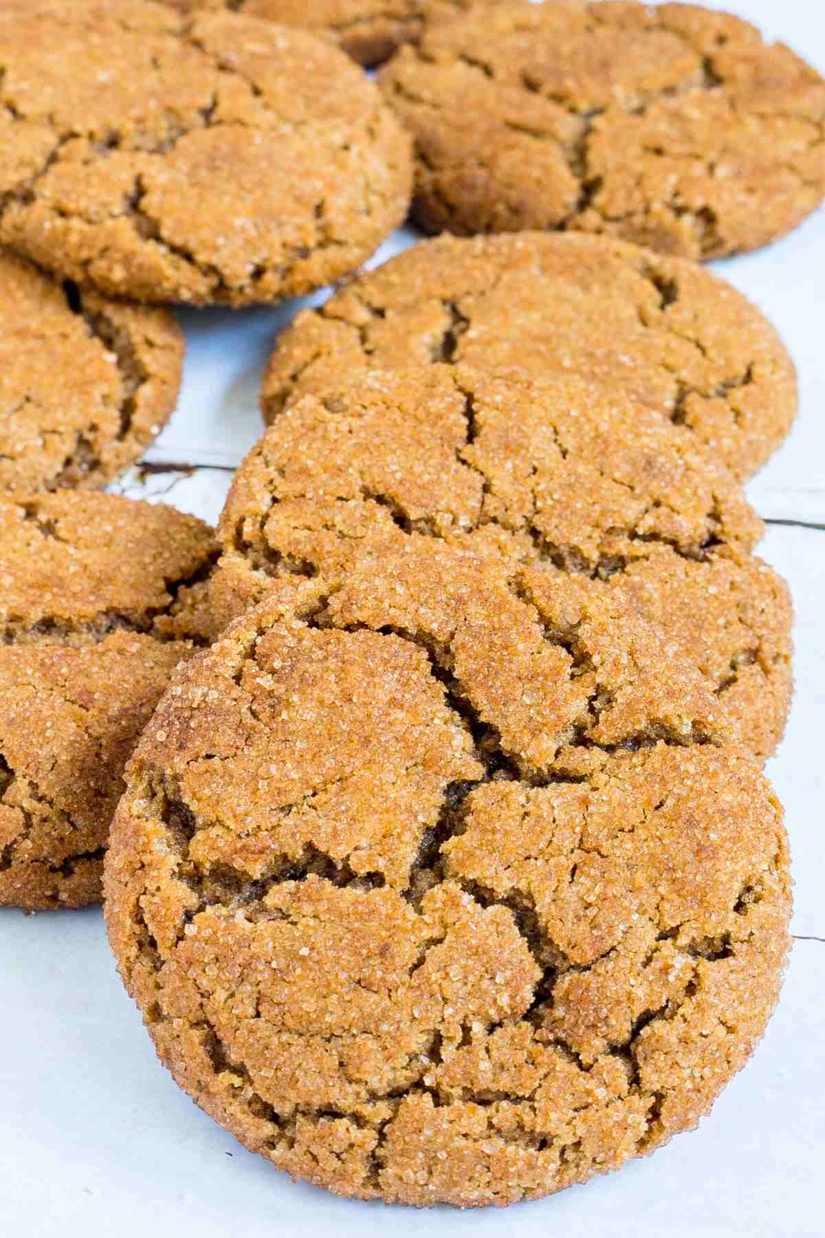 Light brown cookies with crinkled top on a white wooden surface.