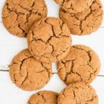 Light brown cookies with crinkled top on a white wooden surface.