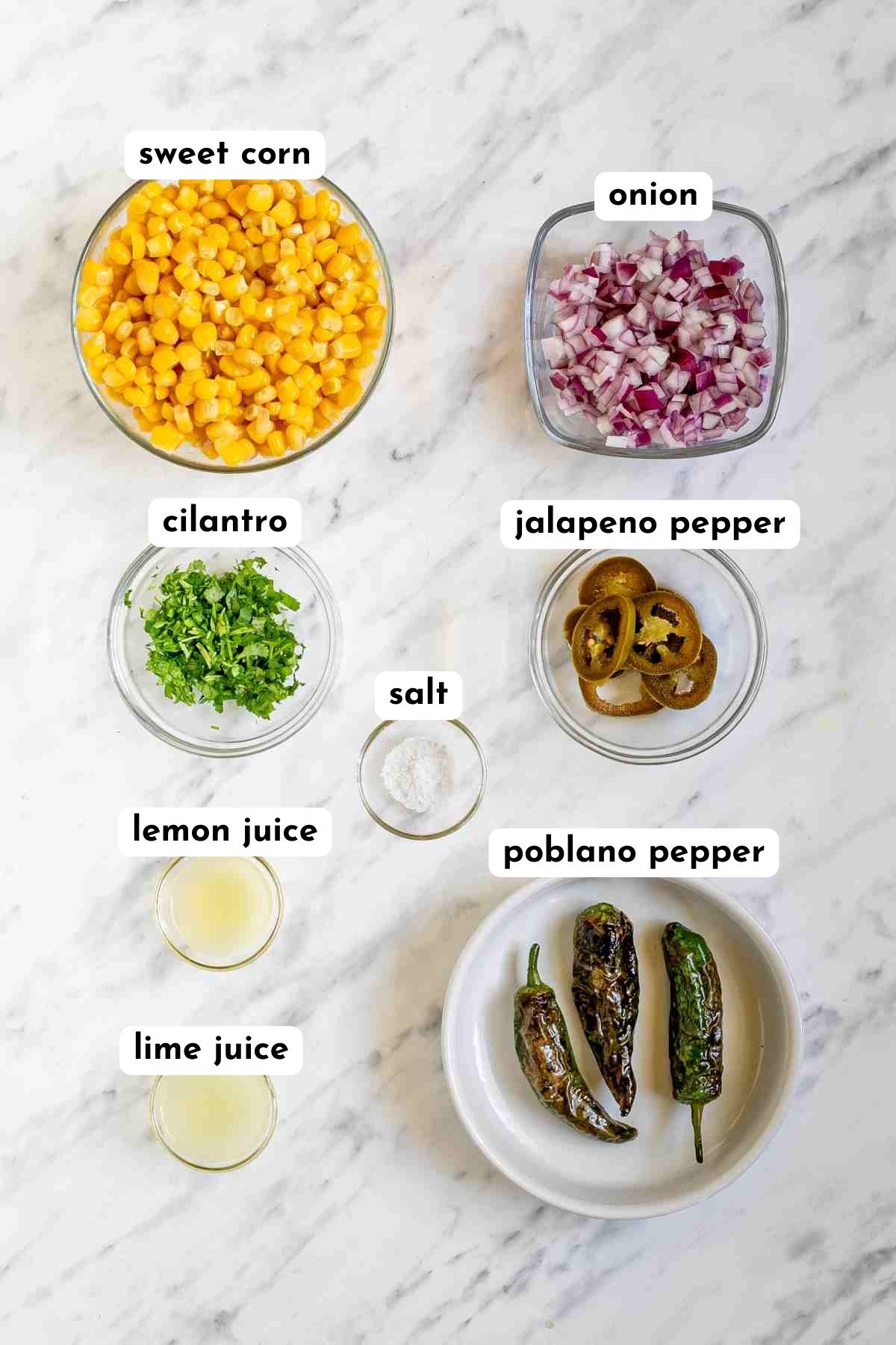 Ingredients of chipotle corn salsa in small glass bowls like corn, chopped red onion, green chilies, and so on.
