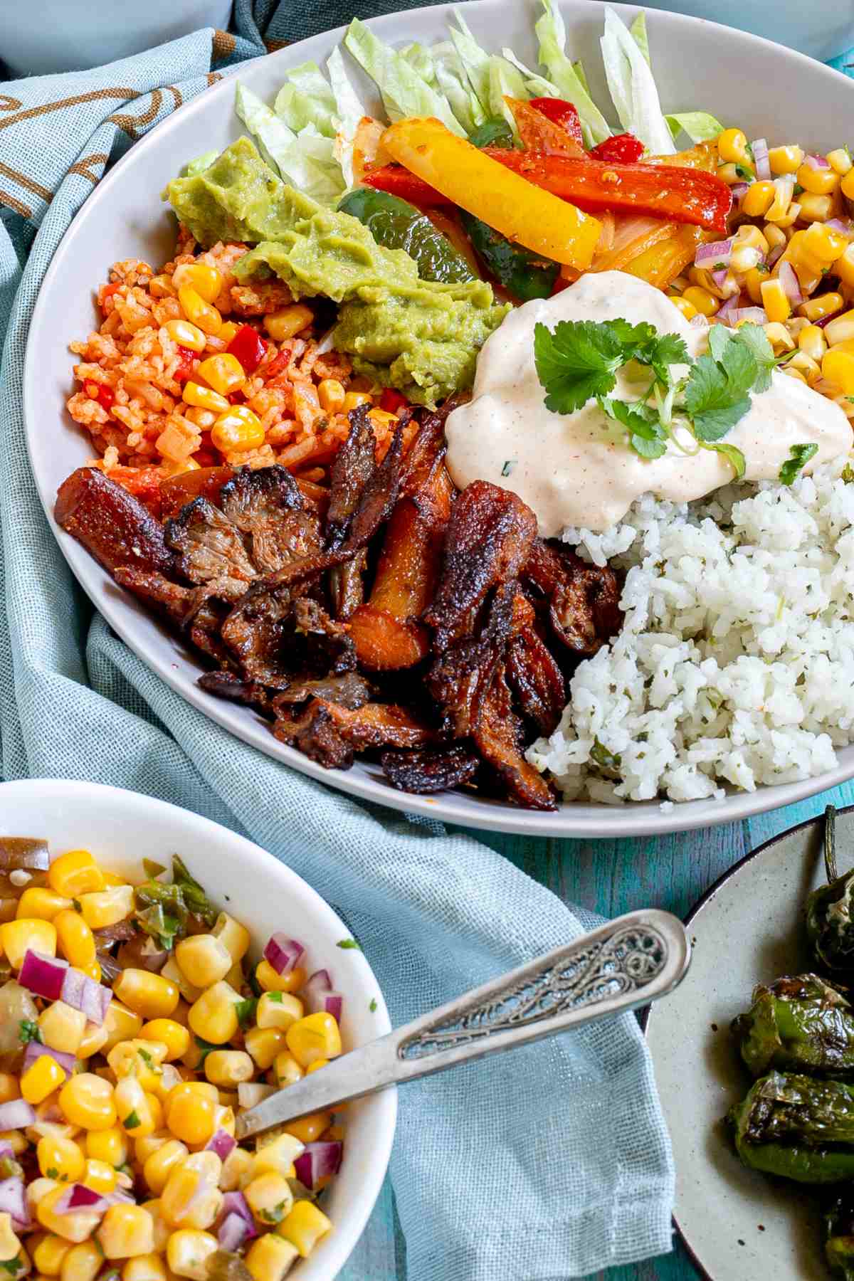 White bowl with cilantro lime rice, corn salsa, mushroom fajitas, guacamole, fajitas veggies and chipotle mayo.