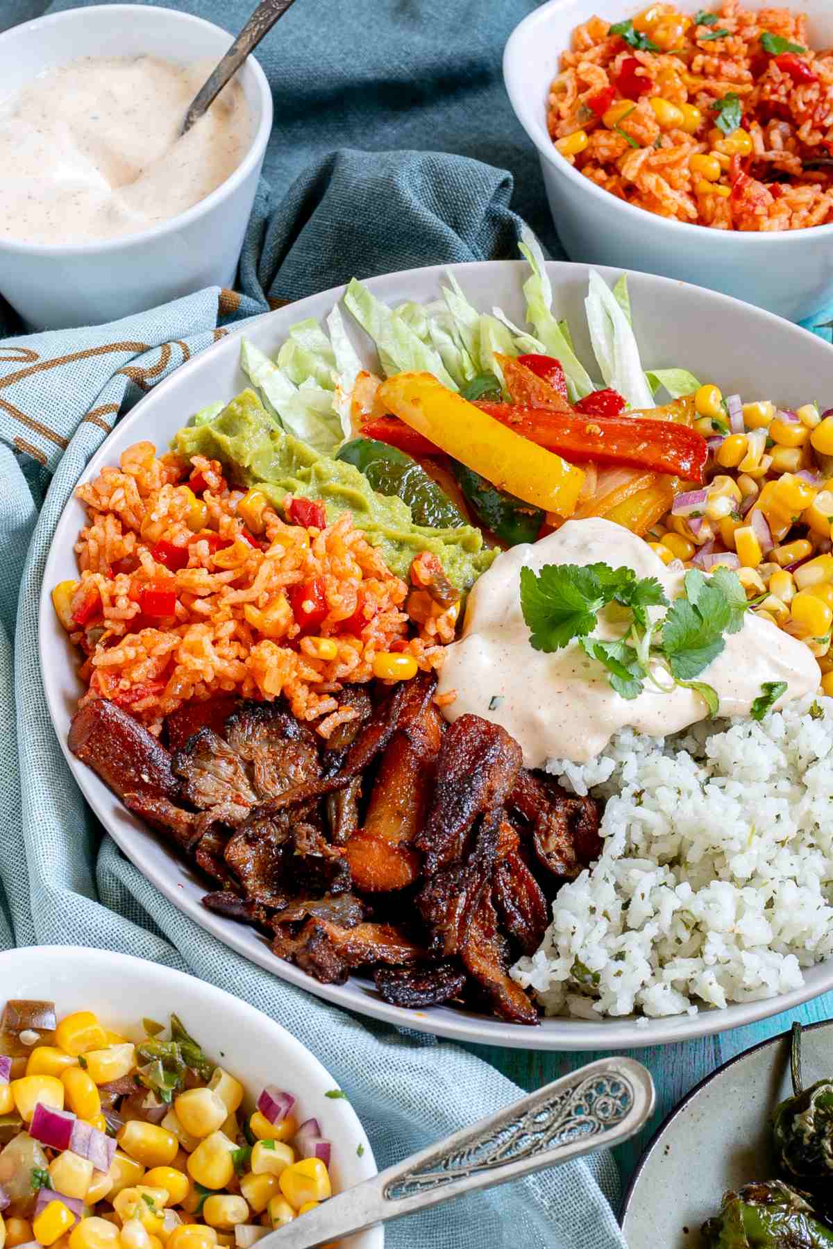 White bowl with cilantro lime rice, corn salsa, mushroom fajitas, guacamole, fajitas veggies and chipotle mayo.