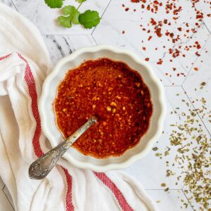 Red thin sauce in a small white bowl with a spoon.