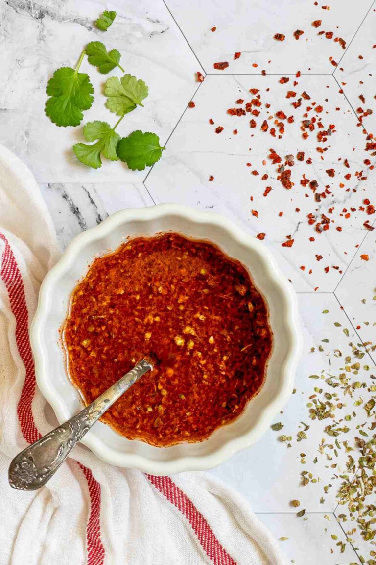 Red thin sauce in a small white bowl with a spoon.