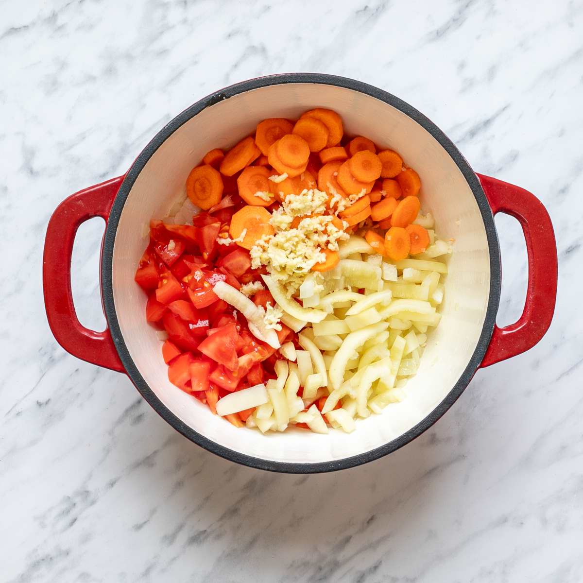 Sliced carrots, chopped tomatoes, Hungarian wax peppers, and garlic in a Dutch oven to make Hungarian Goulash.