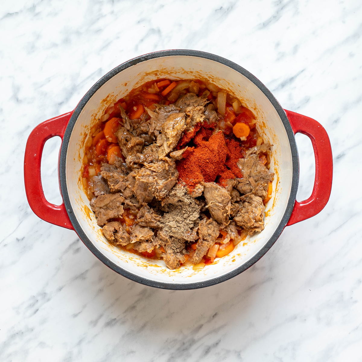 Sauteed sliced carrots, vegetables, and meat in a Dutch oven to make Hungarian Goulash.