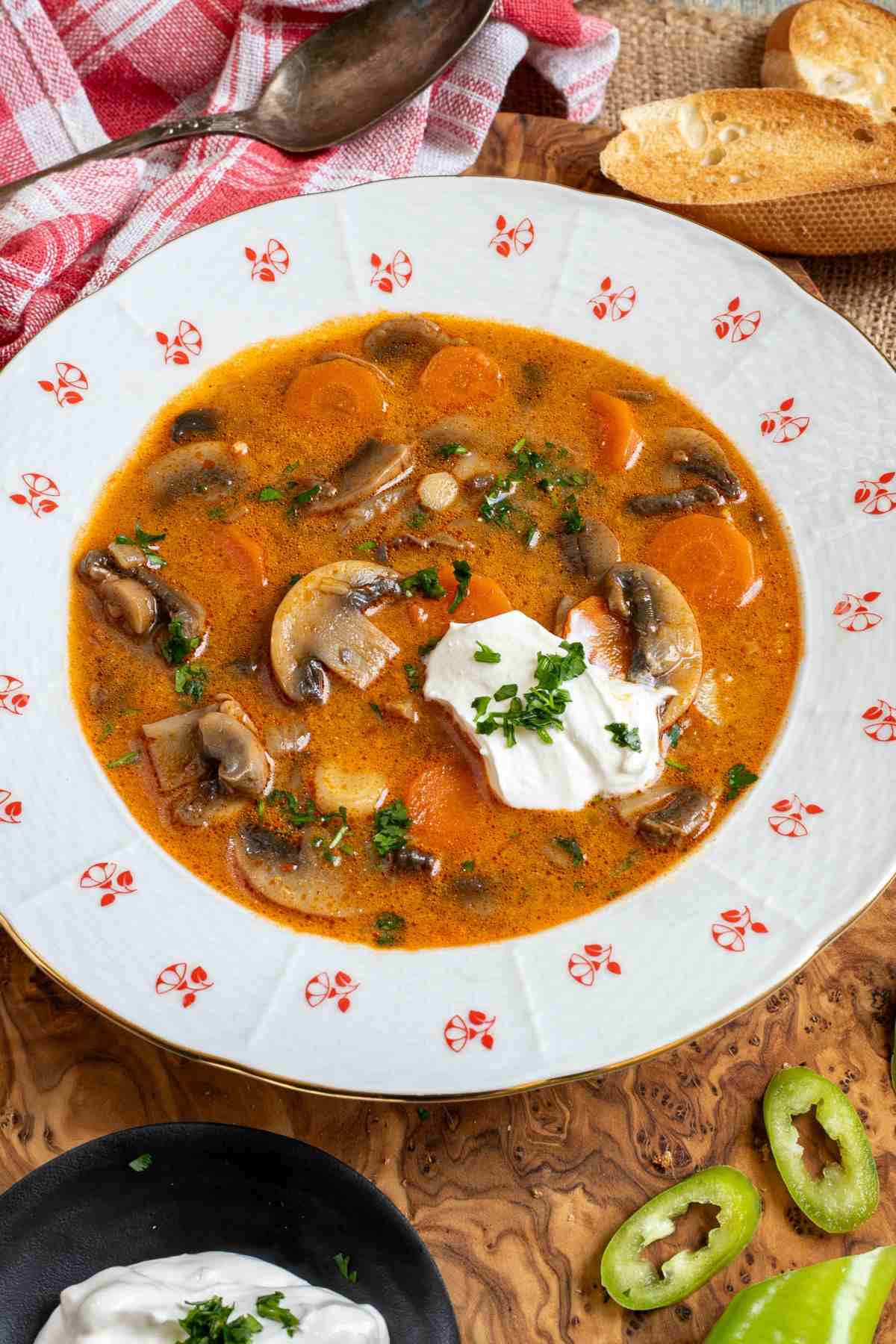 A bowl of Hungarian mushroom soup with sour cream on a wooden cutting board.