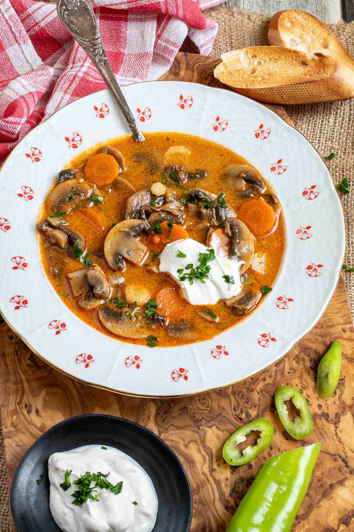 A bowl of Hungarian mushroom soup with sour cream on a wooden cutting board.