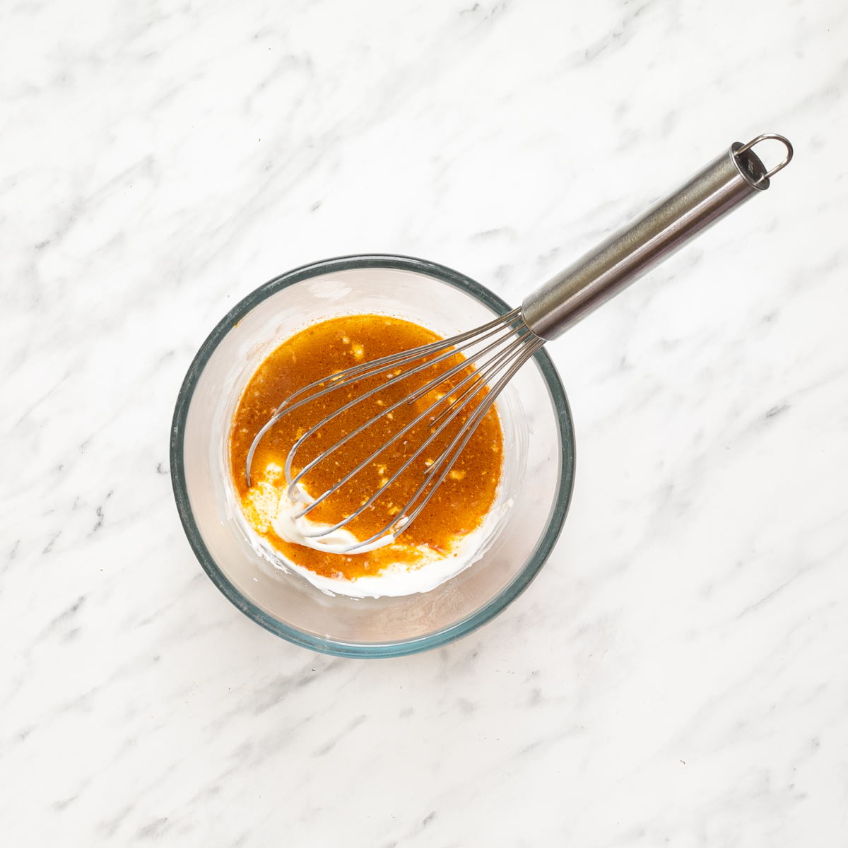 Sour cream and soup mixture being whisked in a small glass bowl to make Hungarian mushroom soup.