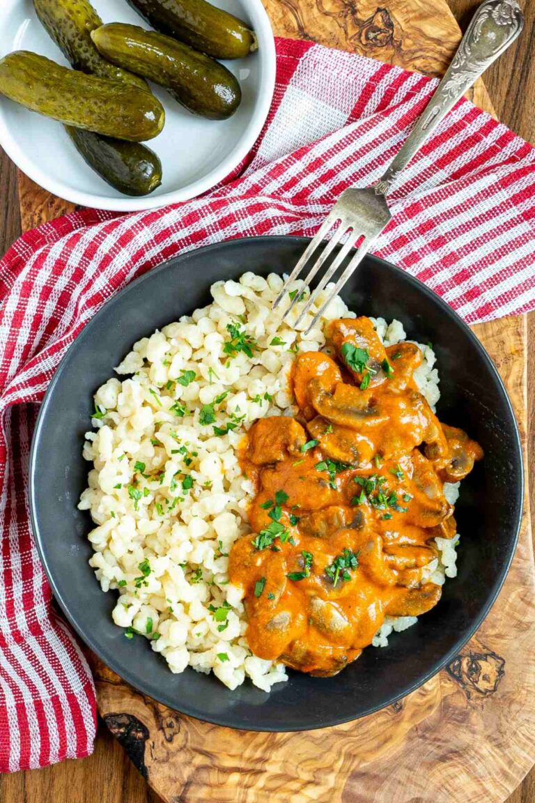 Hungarian mushroom stew over nokedli in a black bowl with a fork on the side.