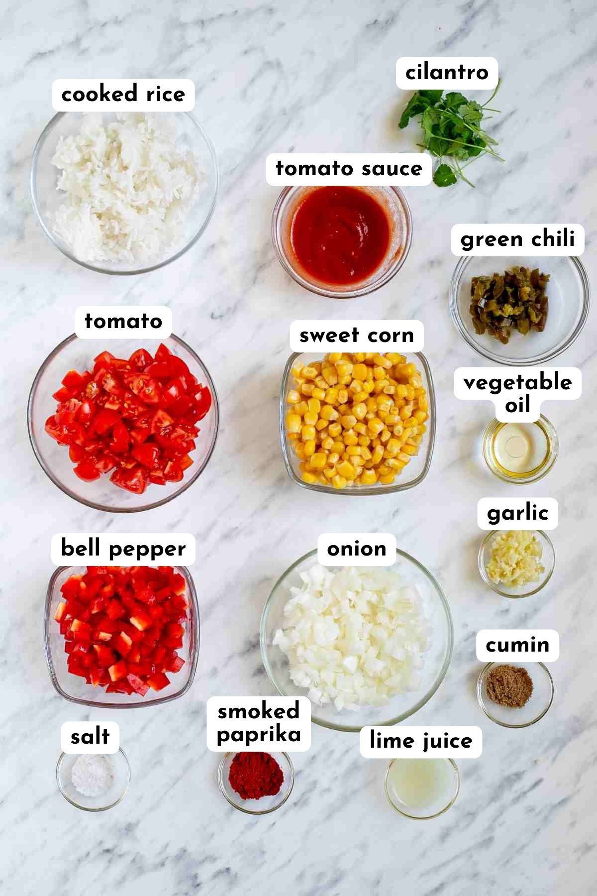 Ingredients of Mexican fried rice in small glass bowls like rice, tomato, bell pepper, corn, red sauce, chopped onion and so on. 