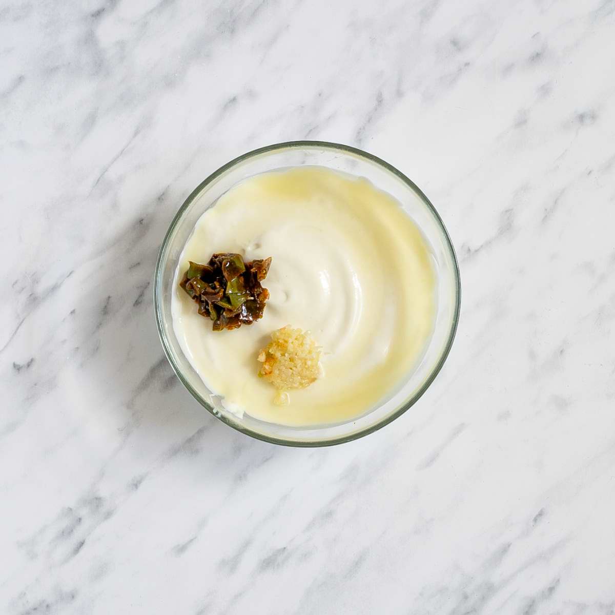 Small glass bowl with mayo, lime juice, finely chopped green peppers and minced garlic.