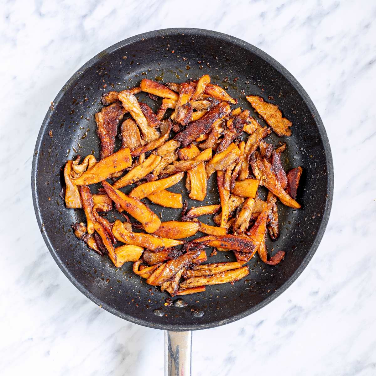 Fried marinated shredded mushrooms in a skillet.
