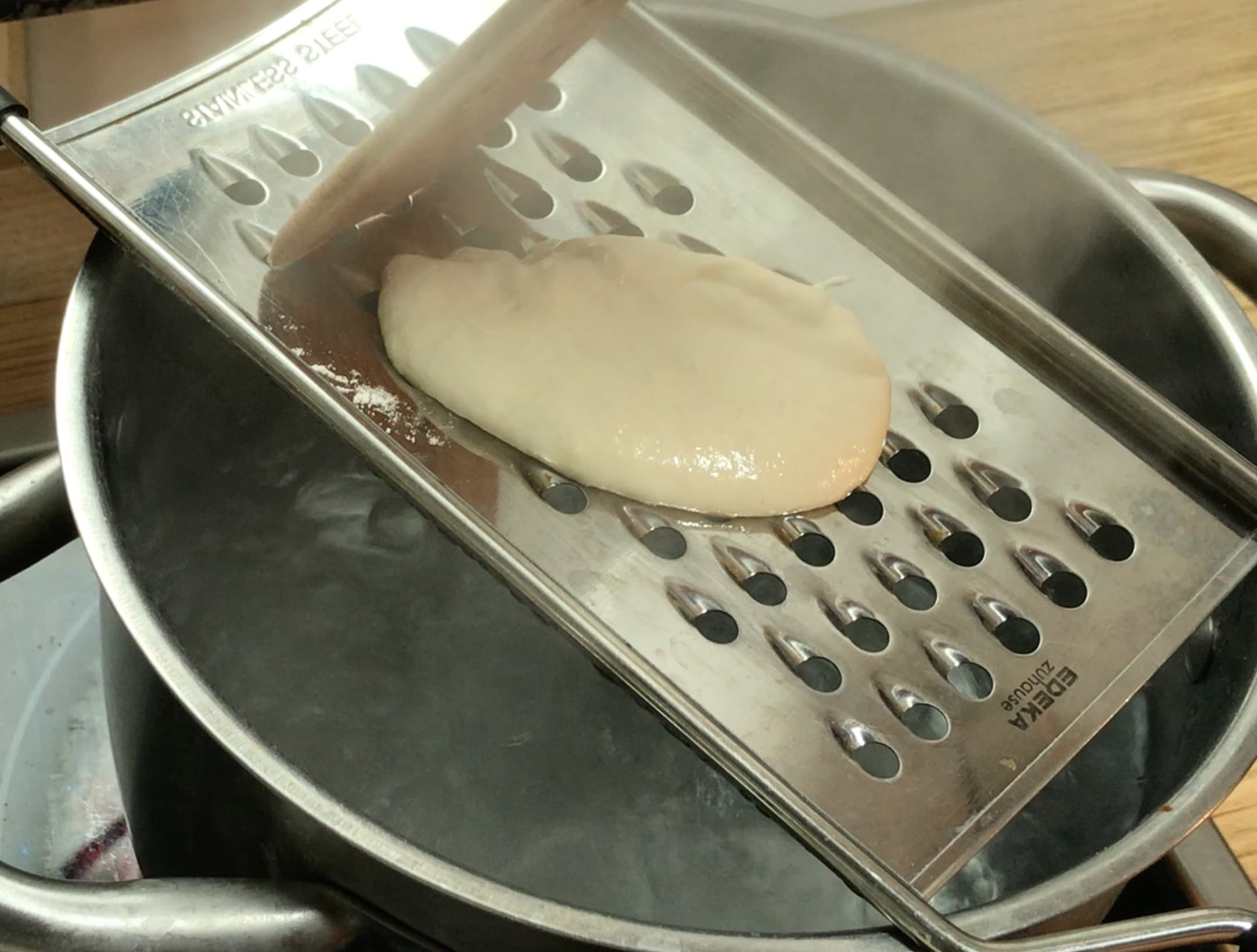 Light brown dough on a spaetzle maker.