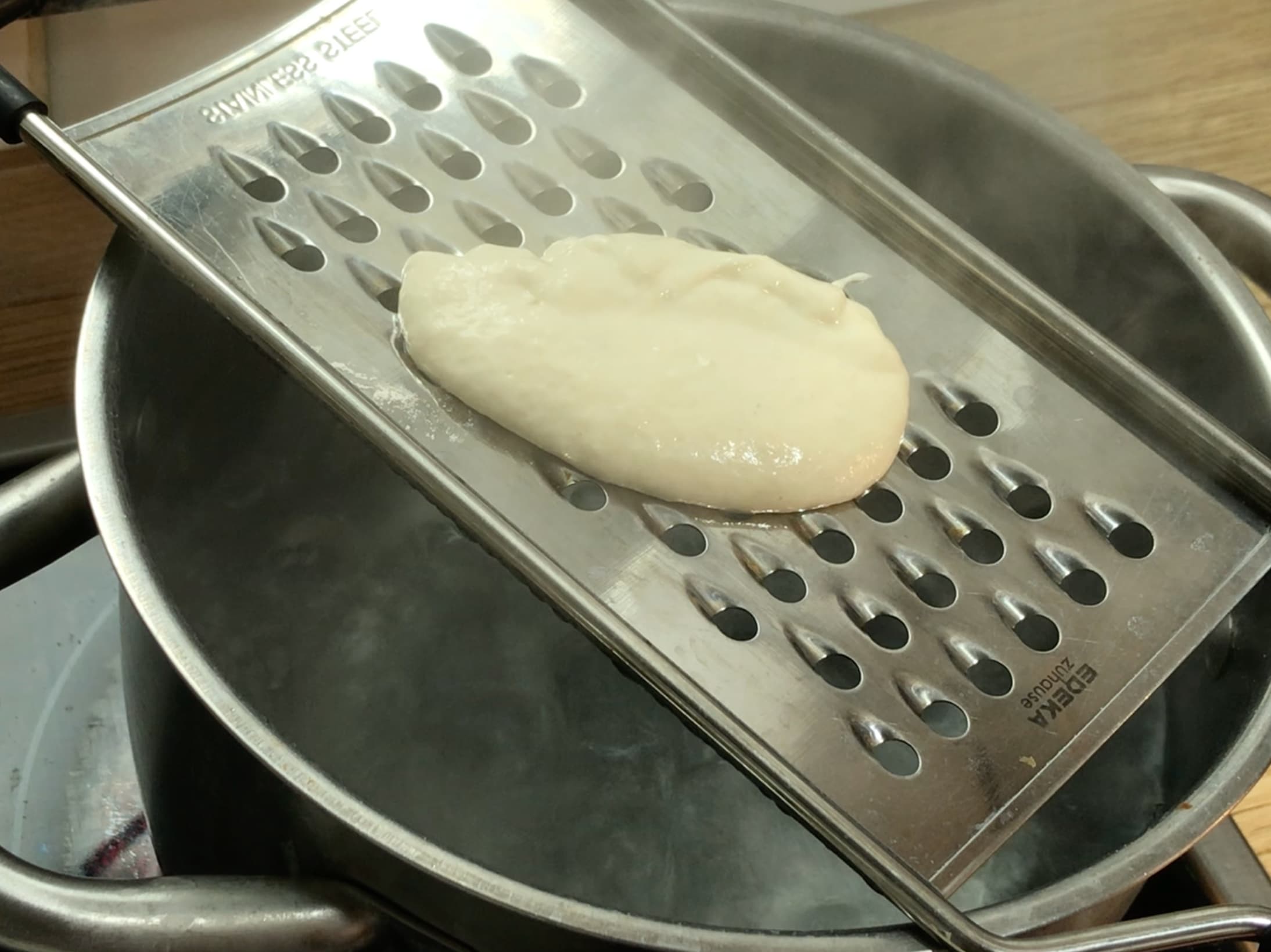 Light brown dough on a spaetzle maker. 
