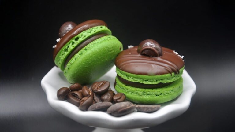 Two green macarons with chocolate and coffee beans