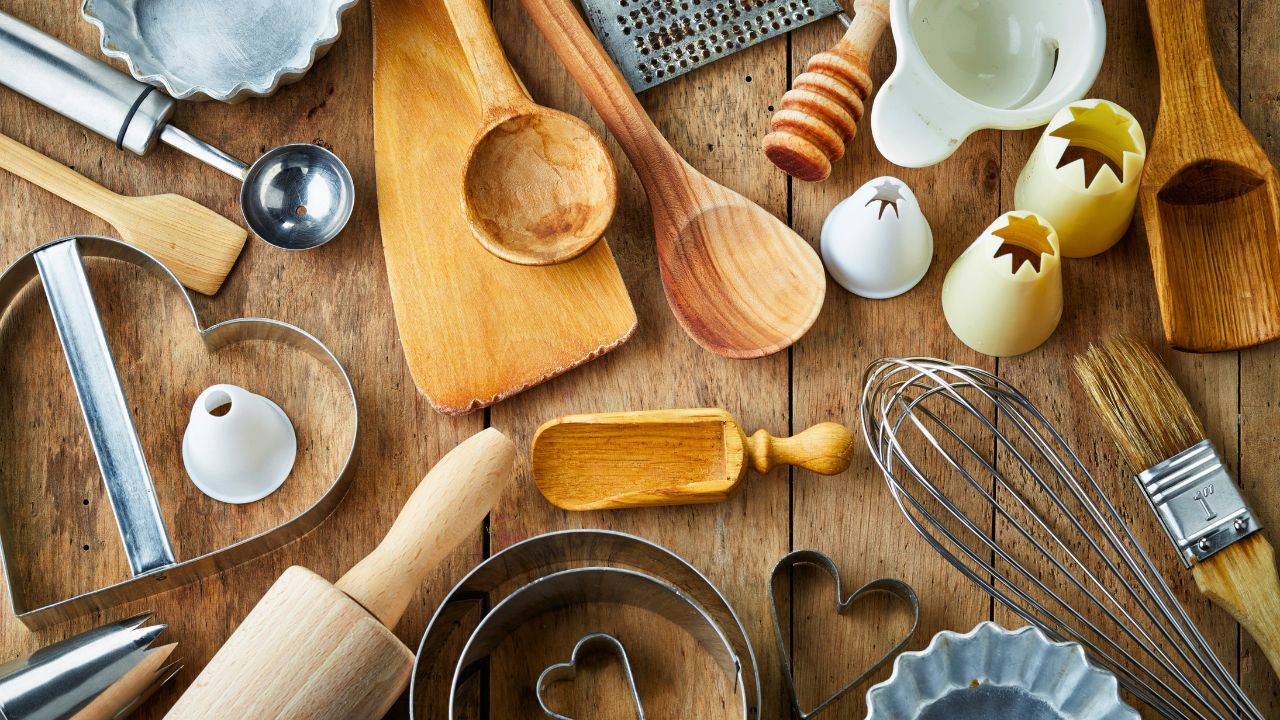 Overhead view of baking tools and cookie cutters arranged on a wooden table.