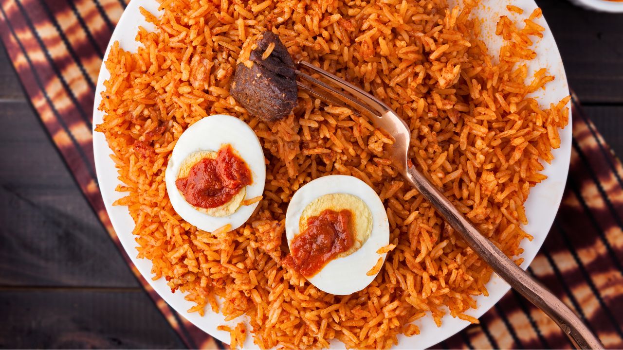 A plate of seasoned rice with hard-boiled eggs, sauce, and a fork on a wooden table.