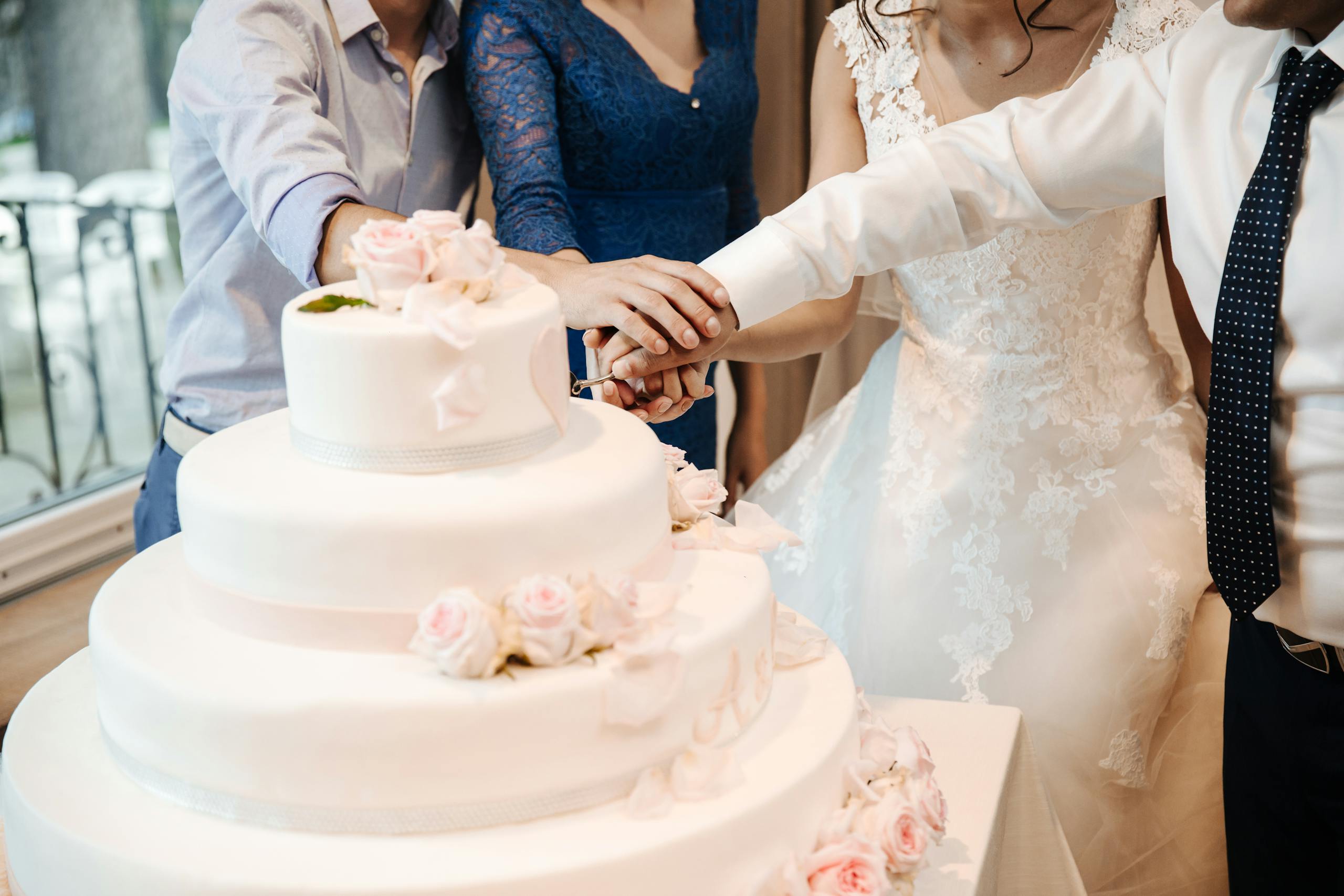 Bride and groom cutting an elegant wedding cake, celebrated in Italy with family and friends.