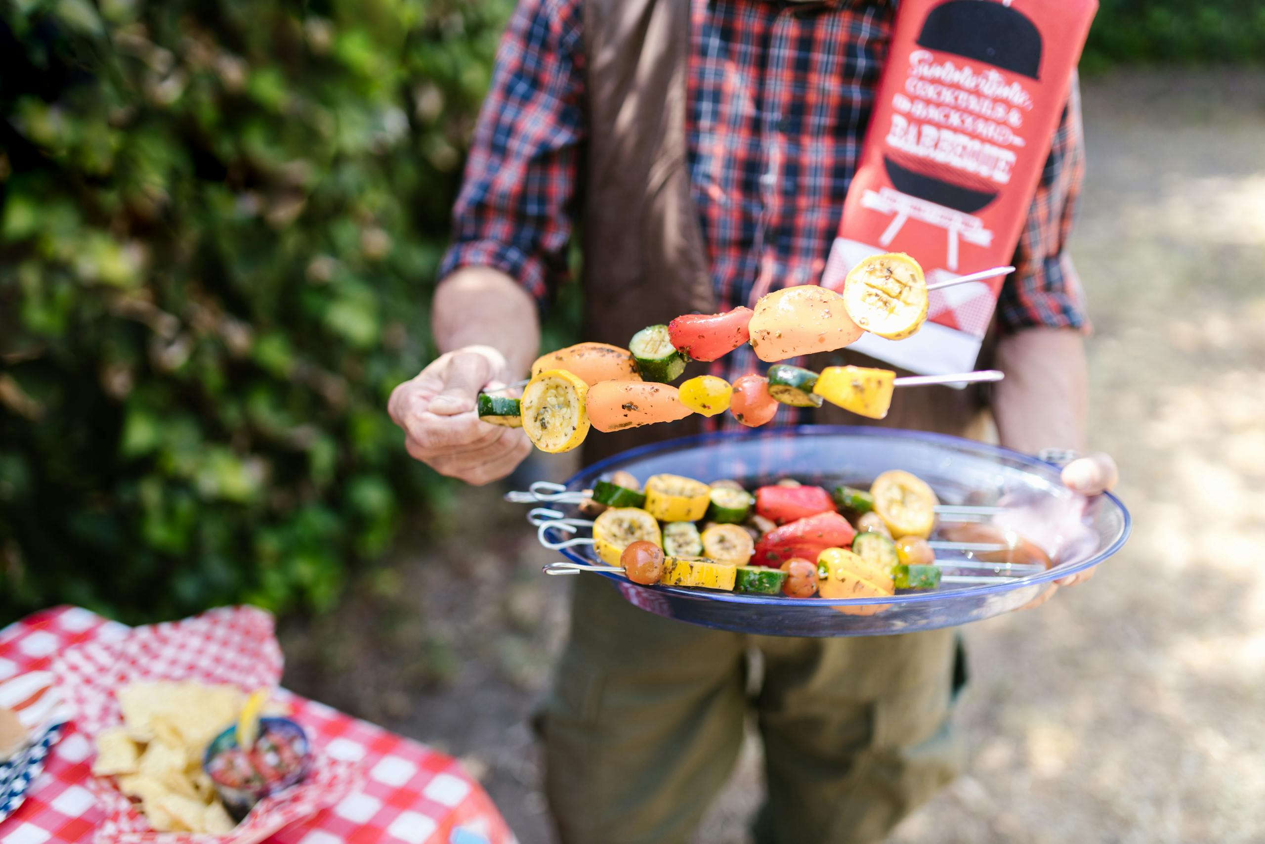 Vibrant vegetable skewers being prepared at an outdoor barbecue during summer.
