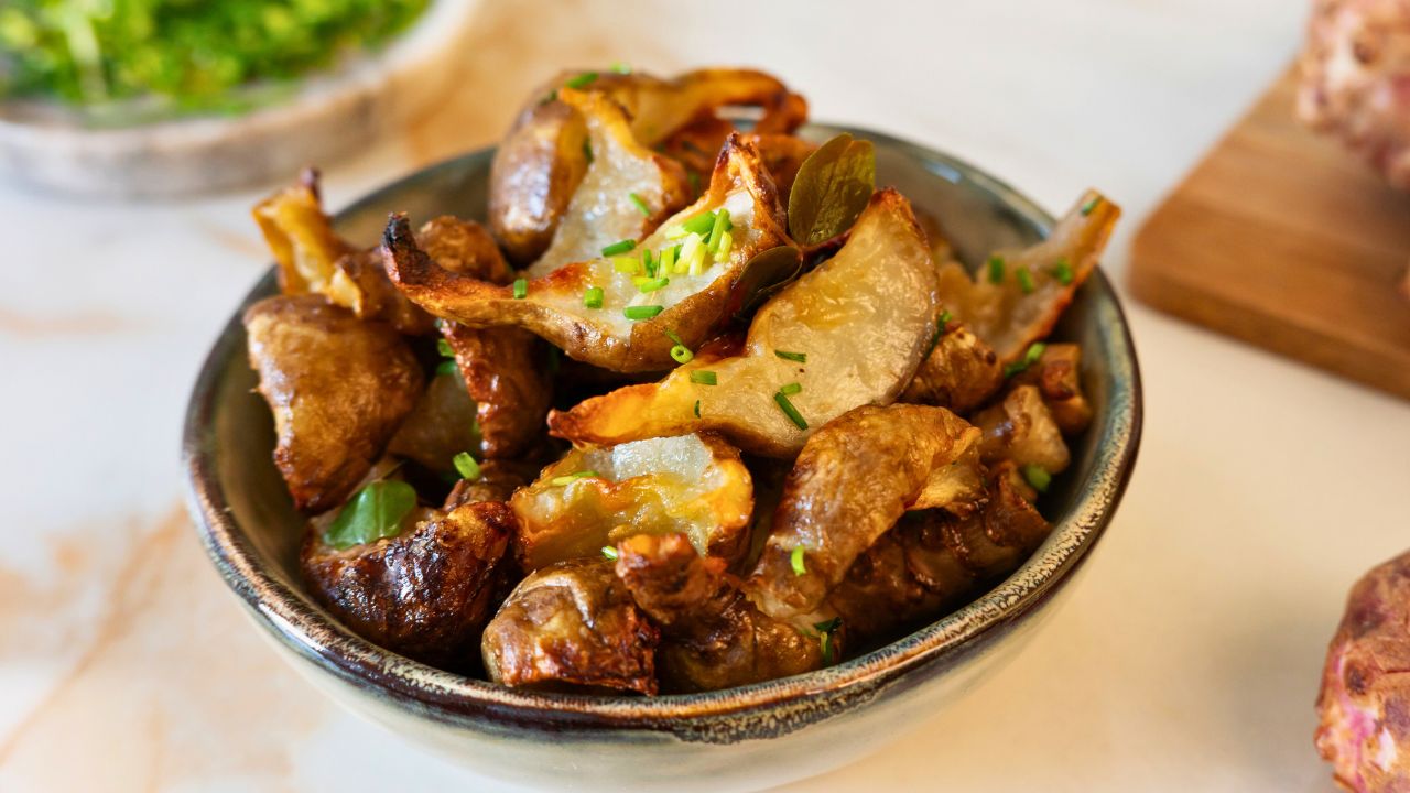 A bowl of roasted mushrooms garnished with chives on a light tabletop.
