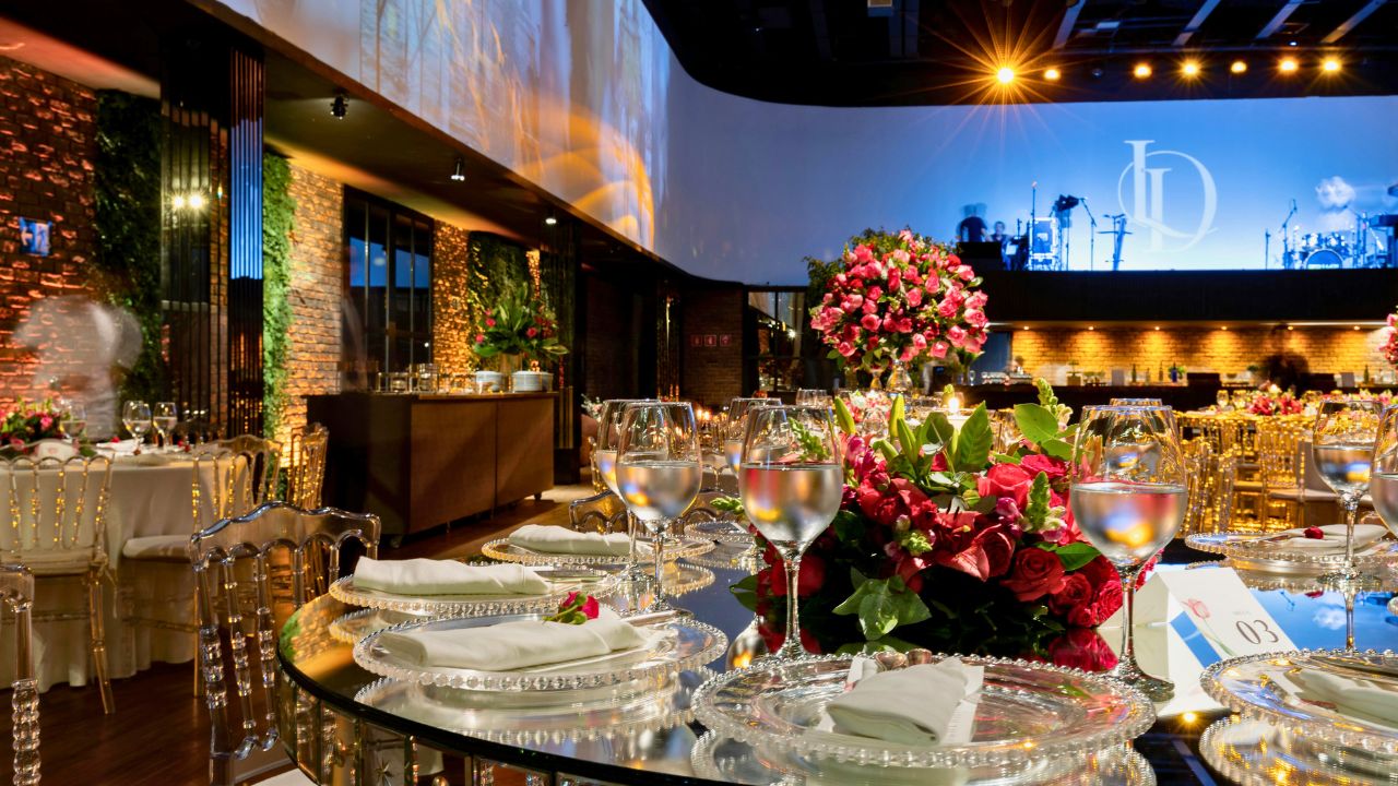 Elegant banquet tables with floral centerpieces and wine glasses in a luxurious event hall.